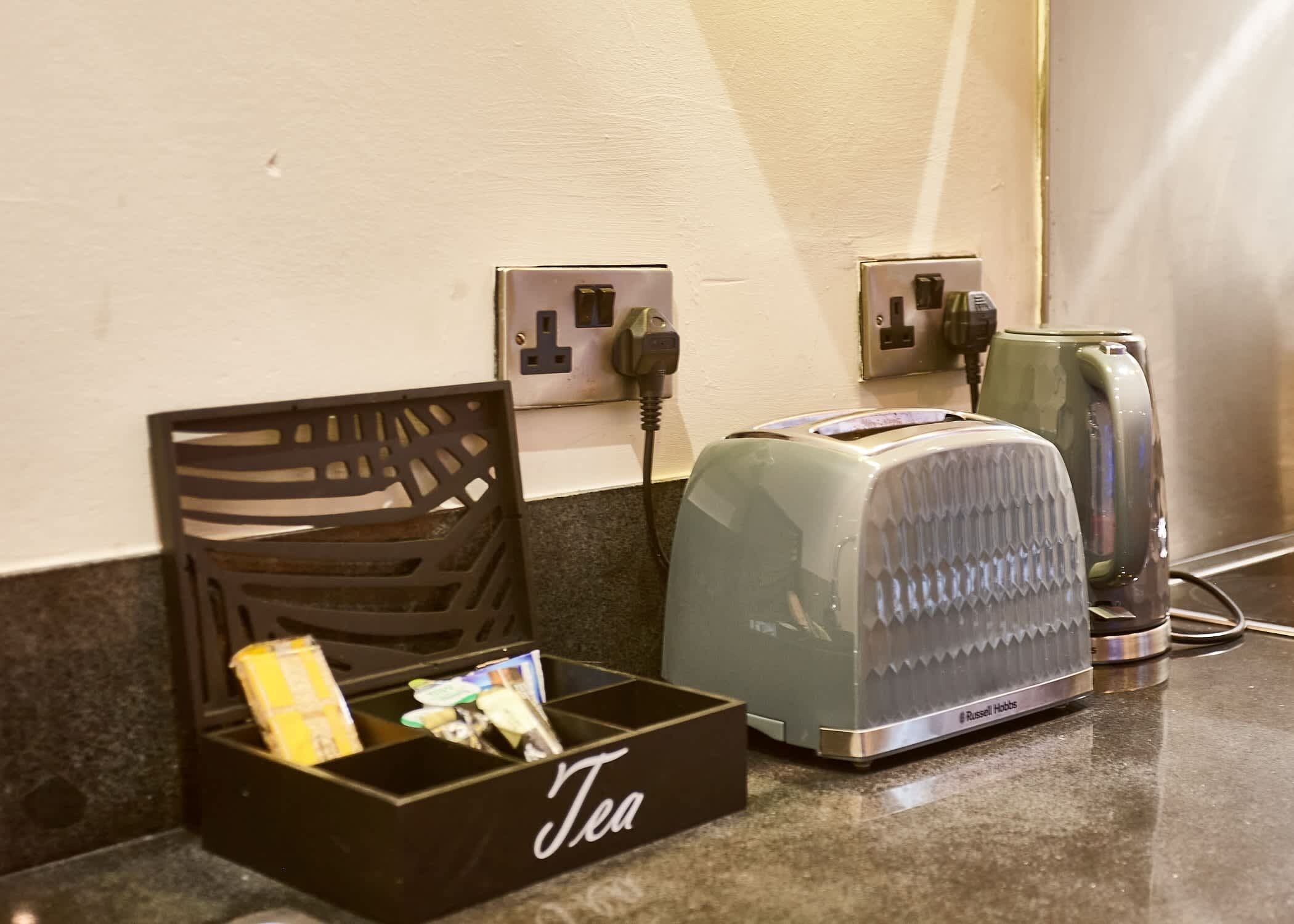 Ein Hotelzimmer mit Teeausstattung, Toaster und Wasserkocher auf der Ablagefläche.