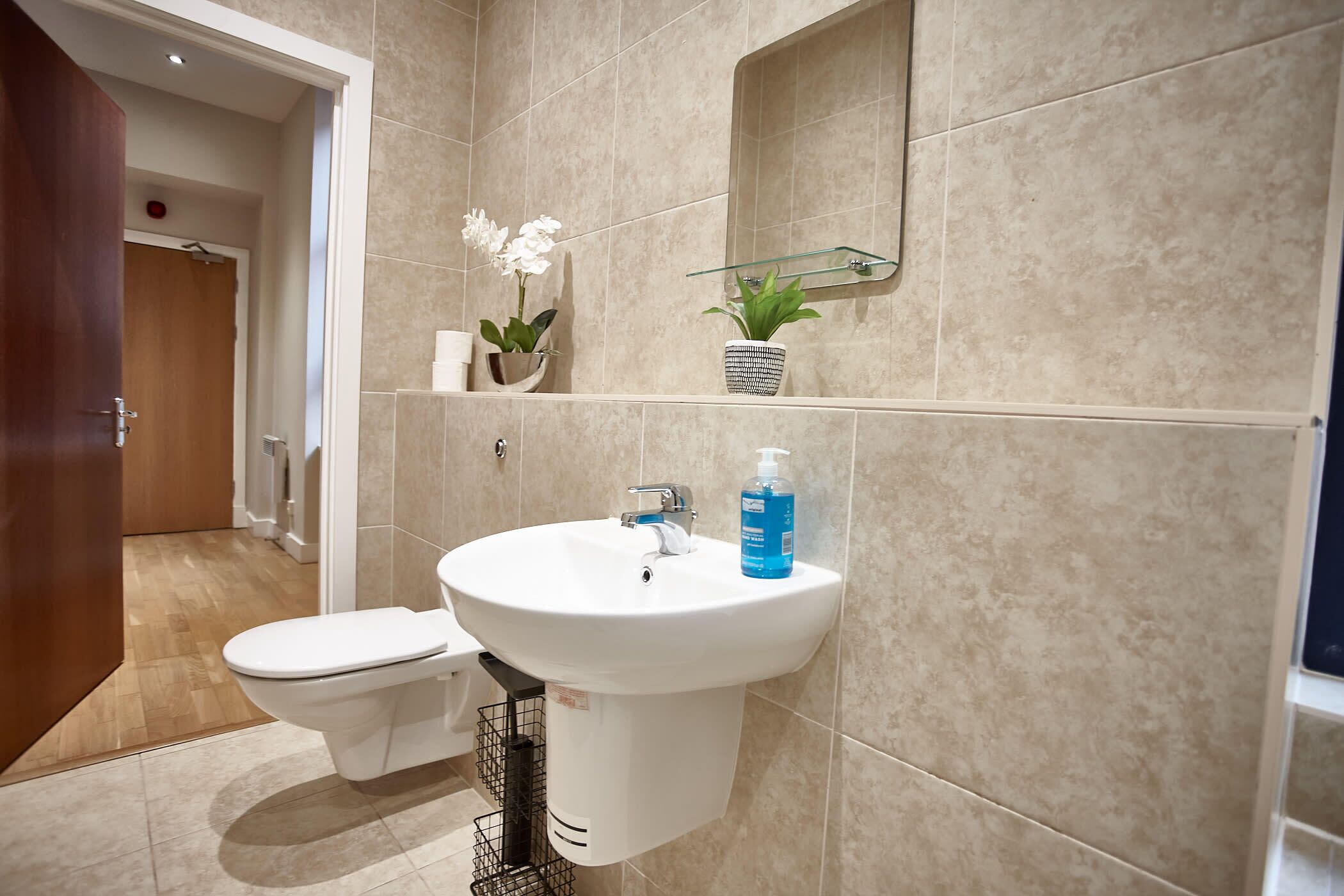 Ein Badezimmer mit Toilette, Waschbecken und zwei Blumentöpfen auf einem Regal.