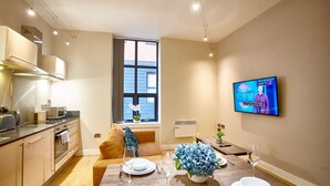 Eine moderne Küche mit Essbereich, einem an der Wand montierten Fernseher und einem Fenster mit Vorhängen.