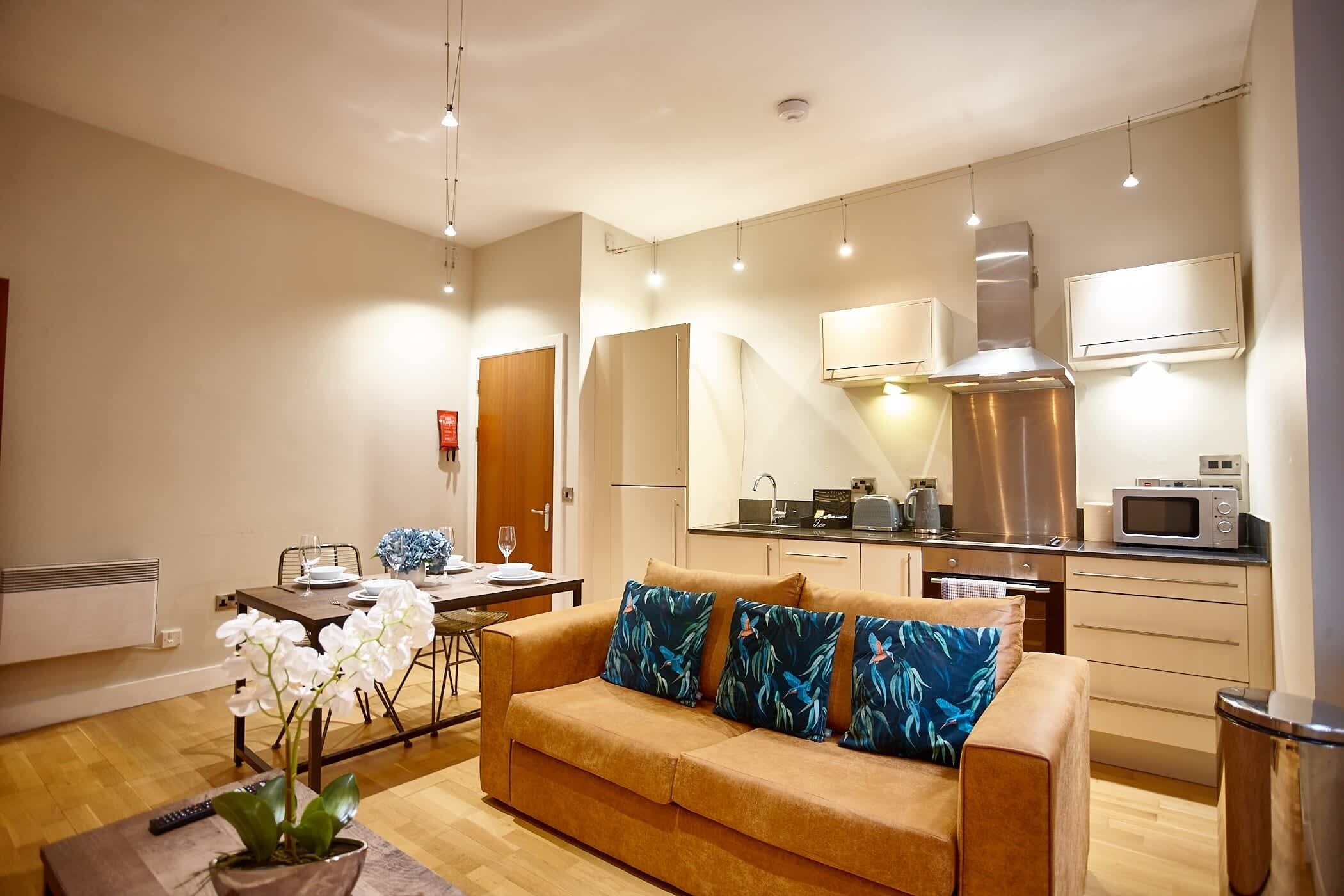 A modern living room with a sofa, a dining table, and a kitchen area with appliances.