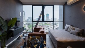 A modern living room with a large window, a sofa, a coffee table, and a TV on a stand. - KLCC CityViewStayCation AT Scarletz Suites By HAPYHOME (Kuala Lumpur)