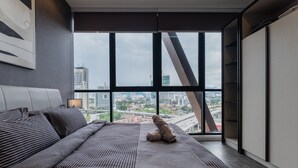 A modern bedroom with a large window, a bed, and a city view. - KLCC CityViewStayCation AT Scarletz Suites By HAPYHOME (Kuala Lumpur)
