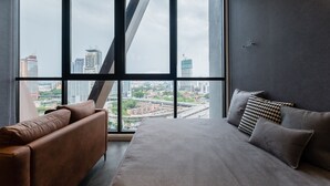 A modern room with a large window, a sofa, and a bed. - KLCC CityViewStayCation AT Scarletz Suites By HAPYHOME (Kuala Lumpur)