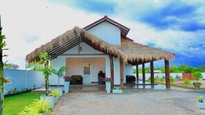 A modern house with a thatched roof, a covered patio, and a well-maintained garden.