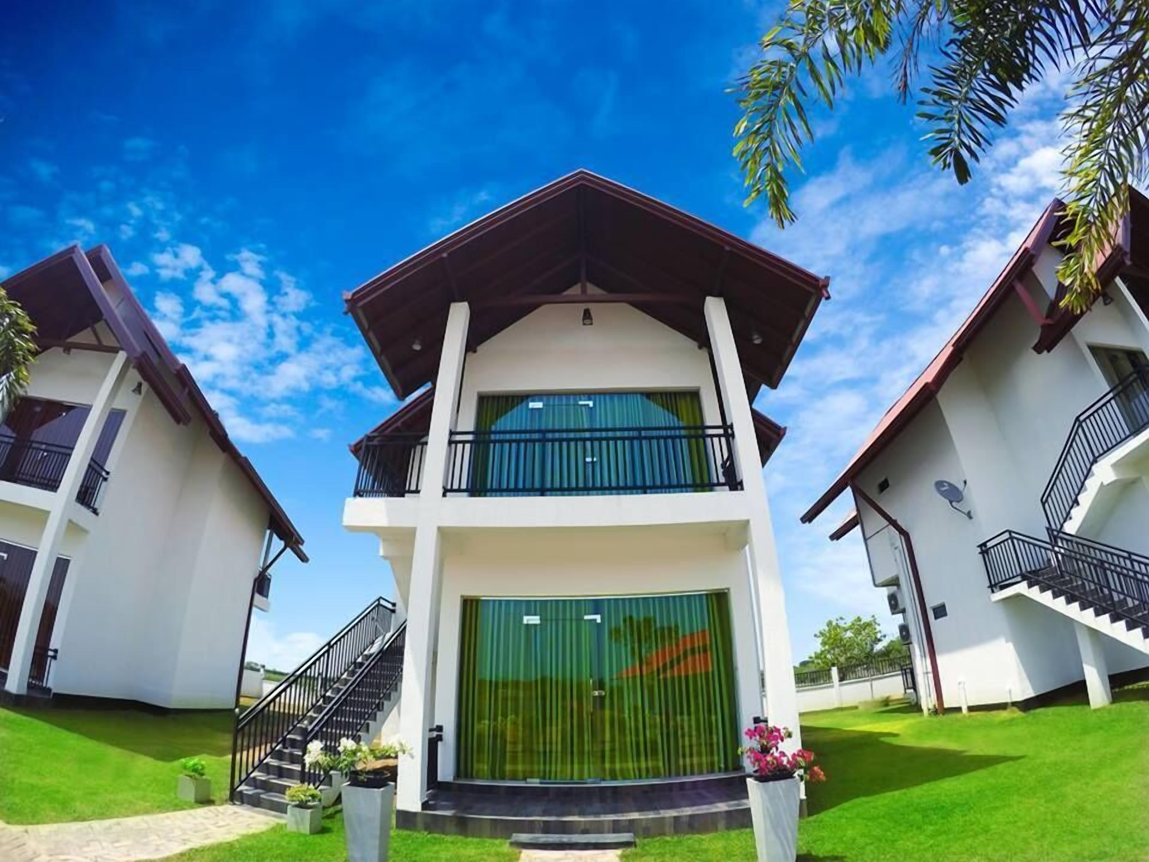 A modern two-story building with a central entrance, balconies, and a staircase leading to the upper floor.