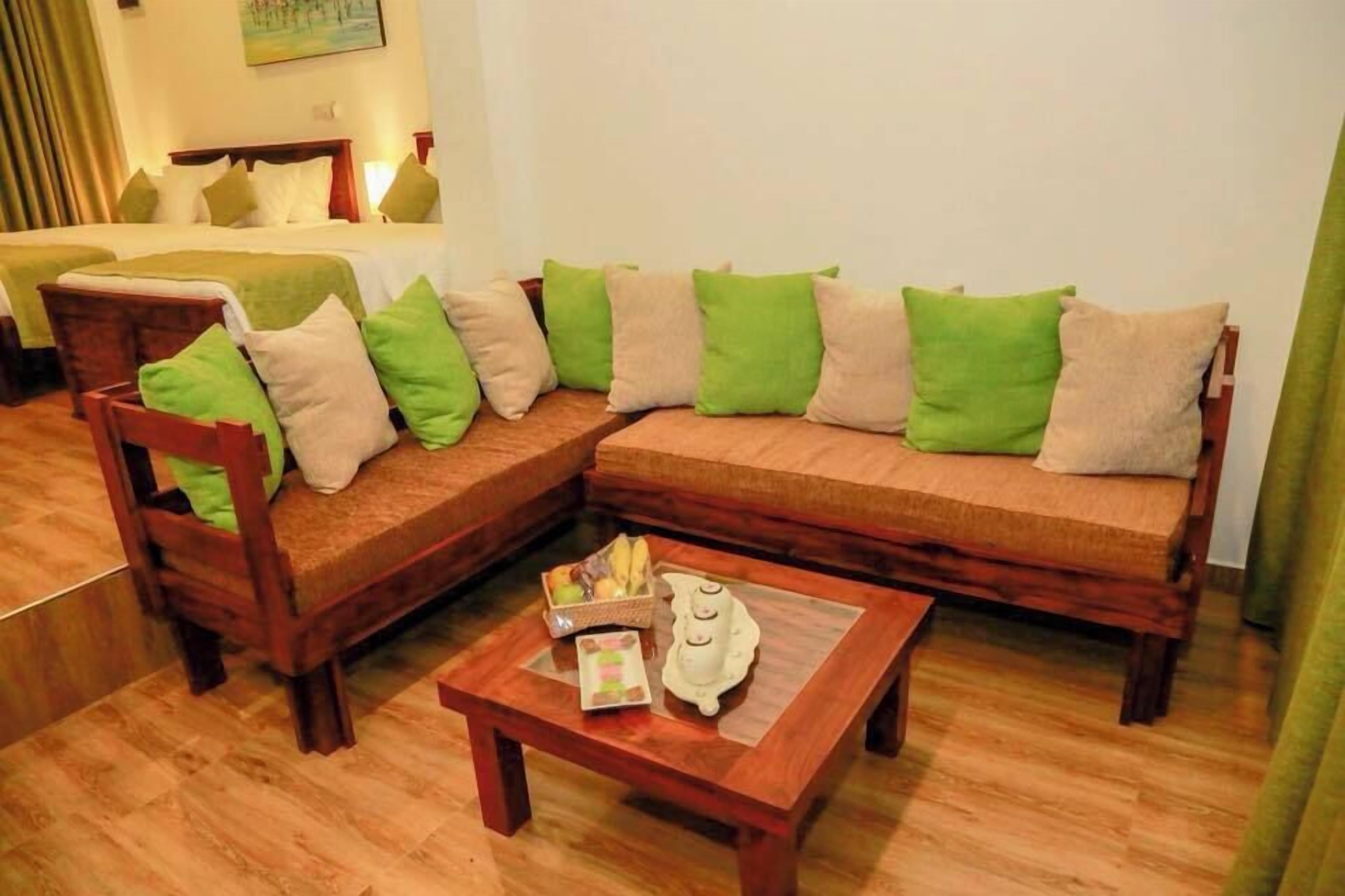 A cozy room with a wooden sofa set, a small table with a decorative item, and a bed in the background.