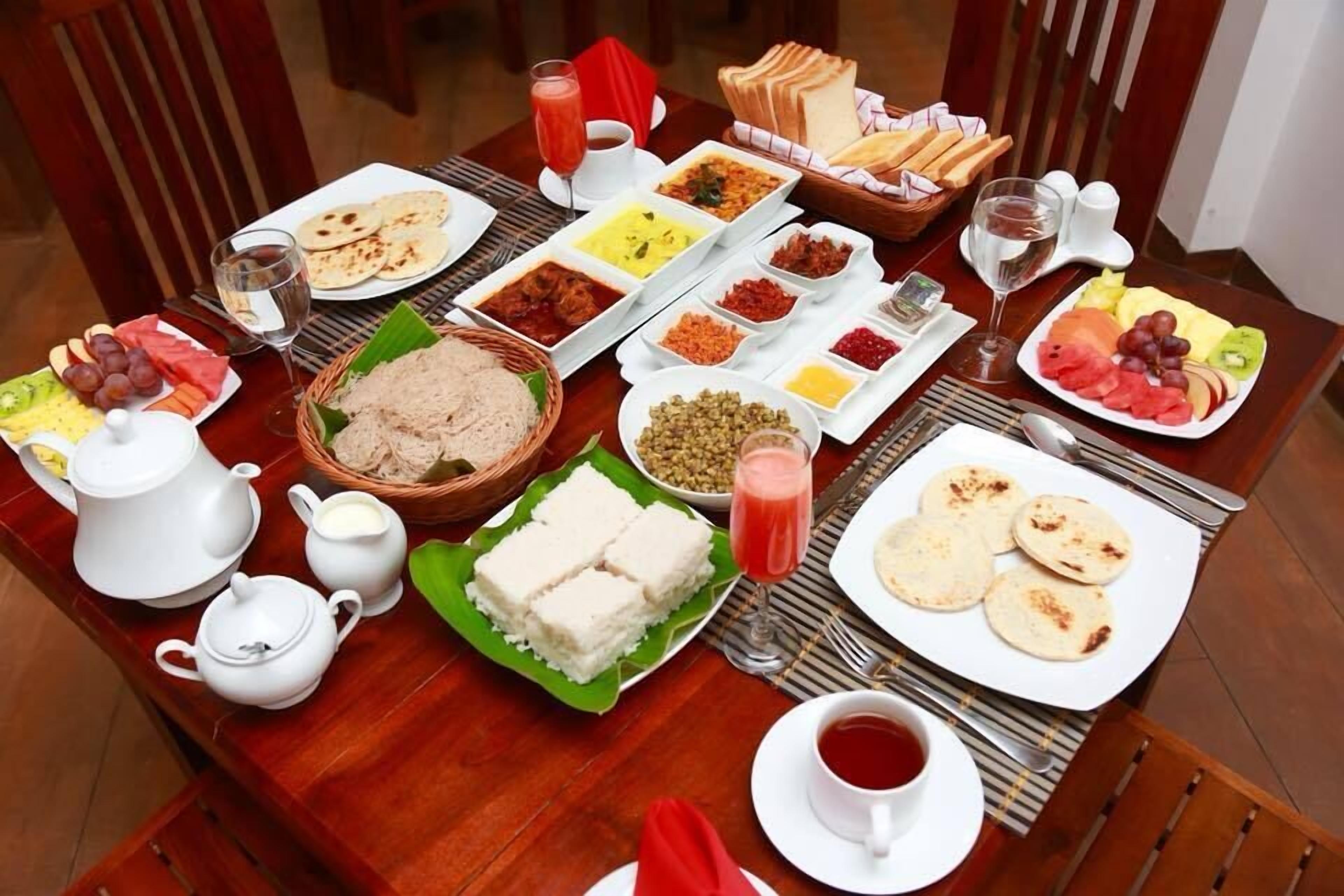 A table set with various dishes, including flatbreads, curries, and fruits, suggesting a meal service.