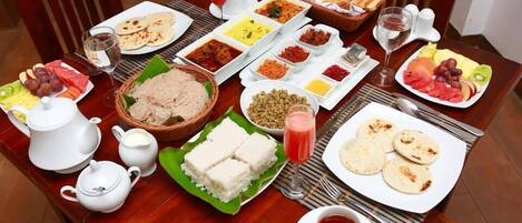 A table set with various dishes, including flatbreads, curries, and fruits, suggesting a meal service.