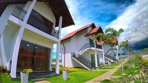 A modern hotel with multiple floors, balconies, and a well-maintained garden.