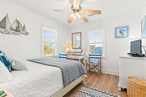 Une chambre à coucher comprenant un lit, un bureau, une chaise et un ventilateur de plafond.