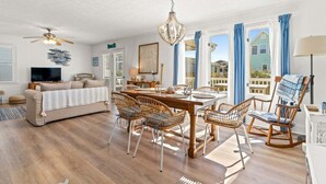 Amplia sala de estar con mesa de comedor, sillas de mimbre, sofá, televisor y ventilador de techo.