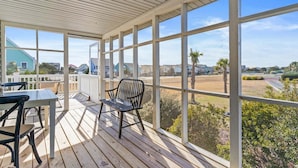 Un patio techado al aire libre con mesa y sillas, ventanas amplias y vistas del vecindario.