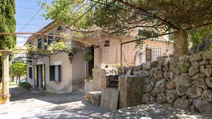 A stone wall, a wooden table, and a building with a rustic appearance. - Finca Es Coste by Rentallorca (Pollensa)