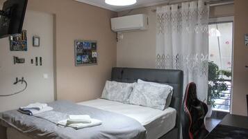 Une chambre d’hôtel avec un lit, une chaise, une télévision, un climatiseur et une fenêtre avec des rideaux.