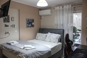 A hotel room with a bed, a chair, a TV, an air conditioner, and a window with curtains.