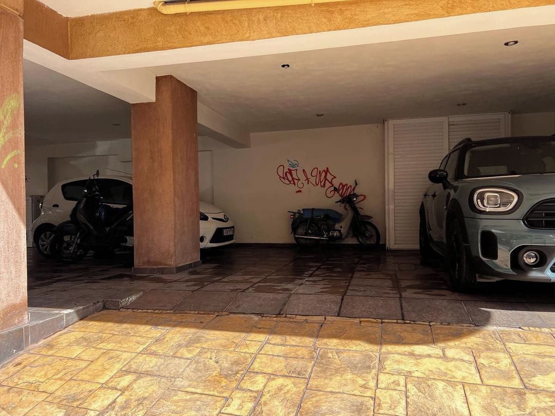 Un estacionamiento techado con una motocicleta y un automóvil estacionados.
