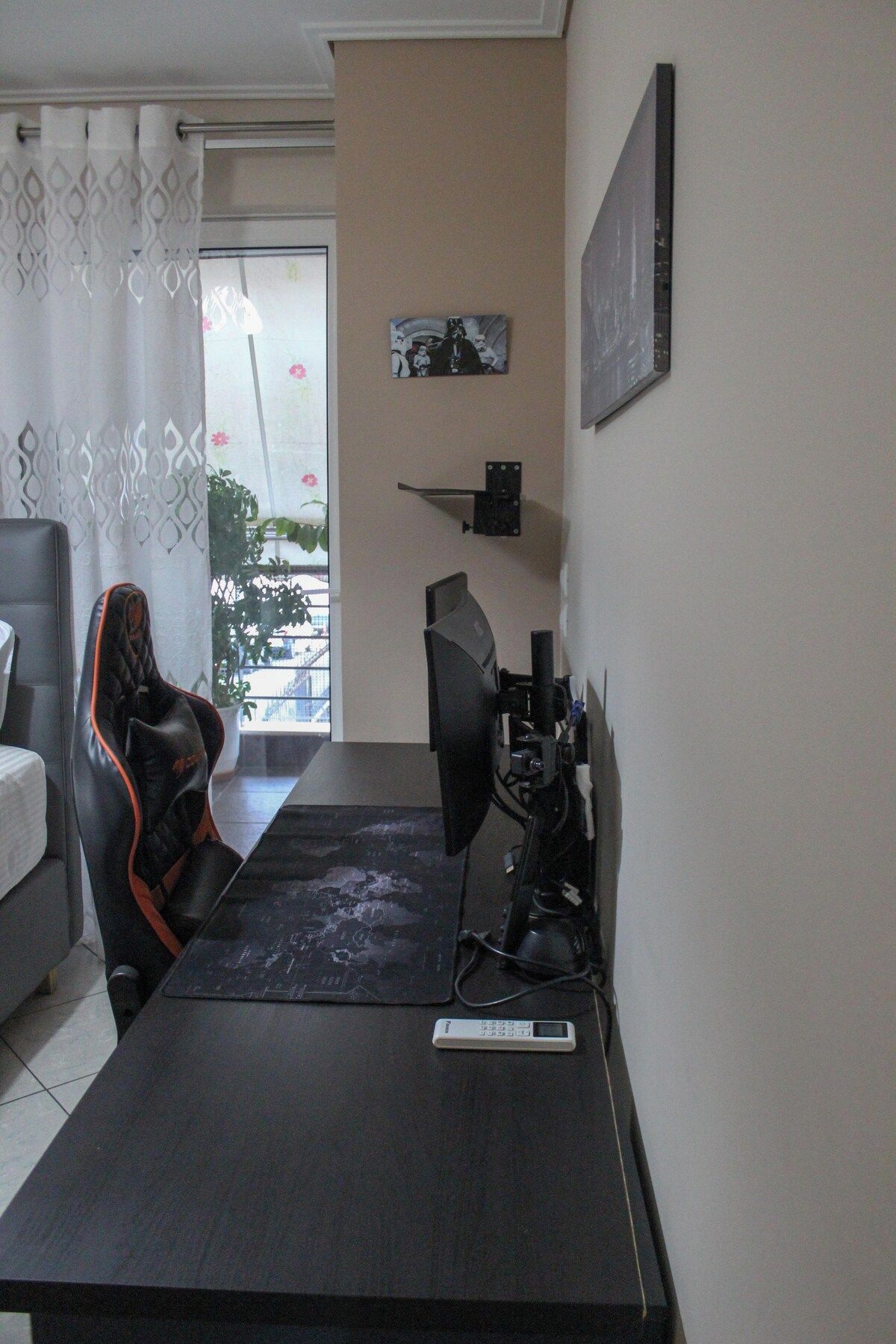 Une pièce comprenant un fauteuil de jeu, un bureau avec un ordinateur et une fenêtre avec des rideaux.