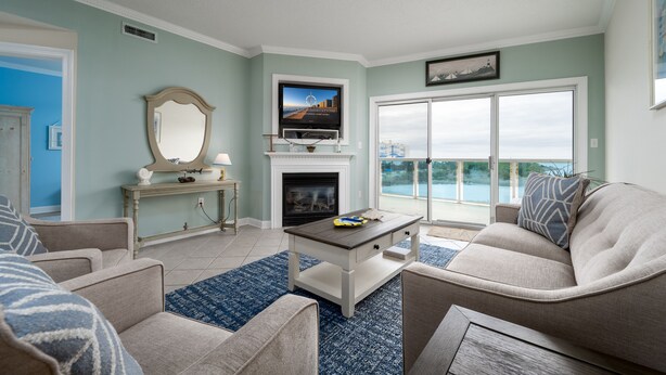 A living room with a fireplace, a television, and a large window overlooking a balcony.