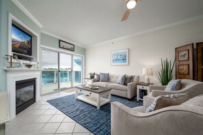 A living room with a fireplace, a television, a sofa, and a coffee table. - Beautiful Bayfront Condo with Stunning View and Pool (Ocean City)