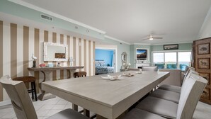 A dining area with a large table, chairs, and a view of the ocean.