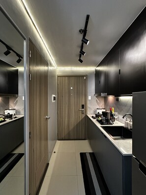 A modern kitchen with dark cabinetry, a wooden door, and a black and white striped rug.