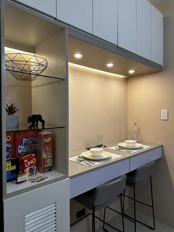 A modern bathroom with a vanity, mirror, and a shelf with board games.