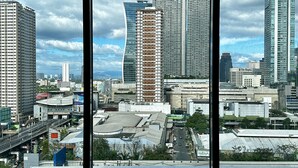 Eine Stadtansicht durch große Fenster, mit modernen Wolkenkratzern, einem geschwungenen Hochhaus und einer Brücke.