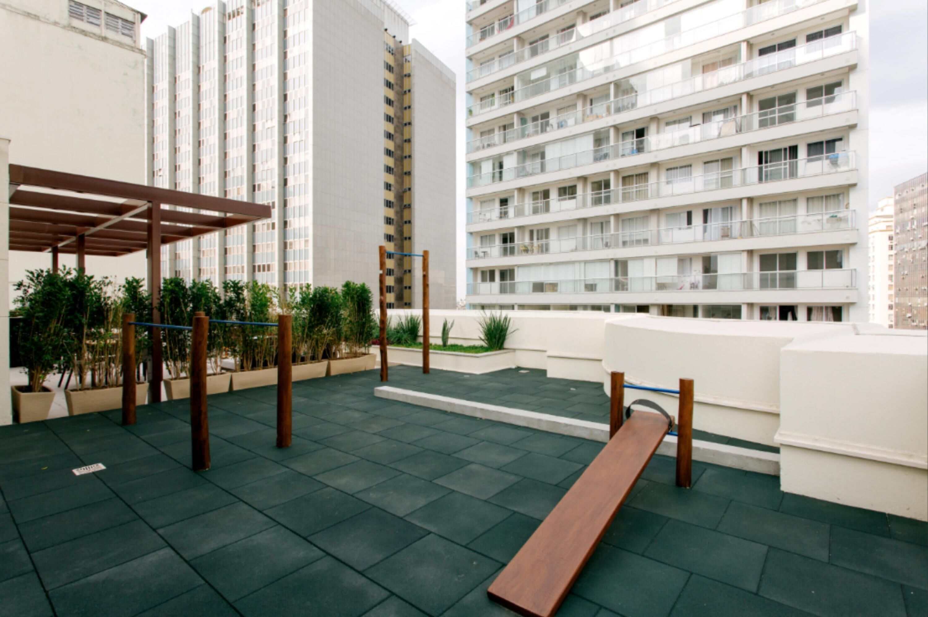 A rooftop terrace with a wooden bench, potted plants, and a pergola.