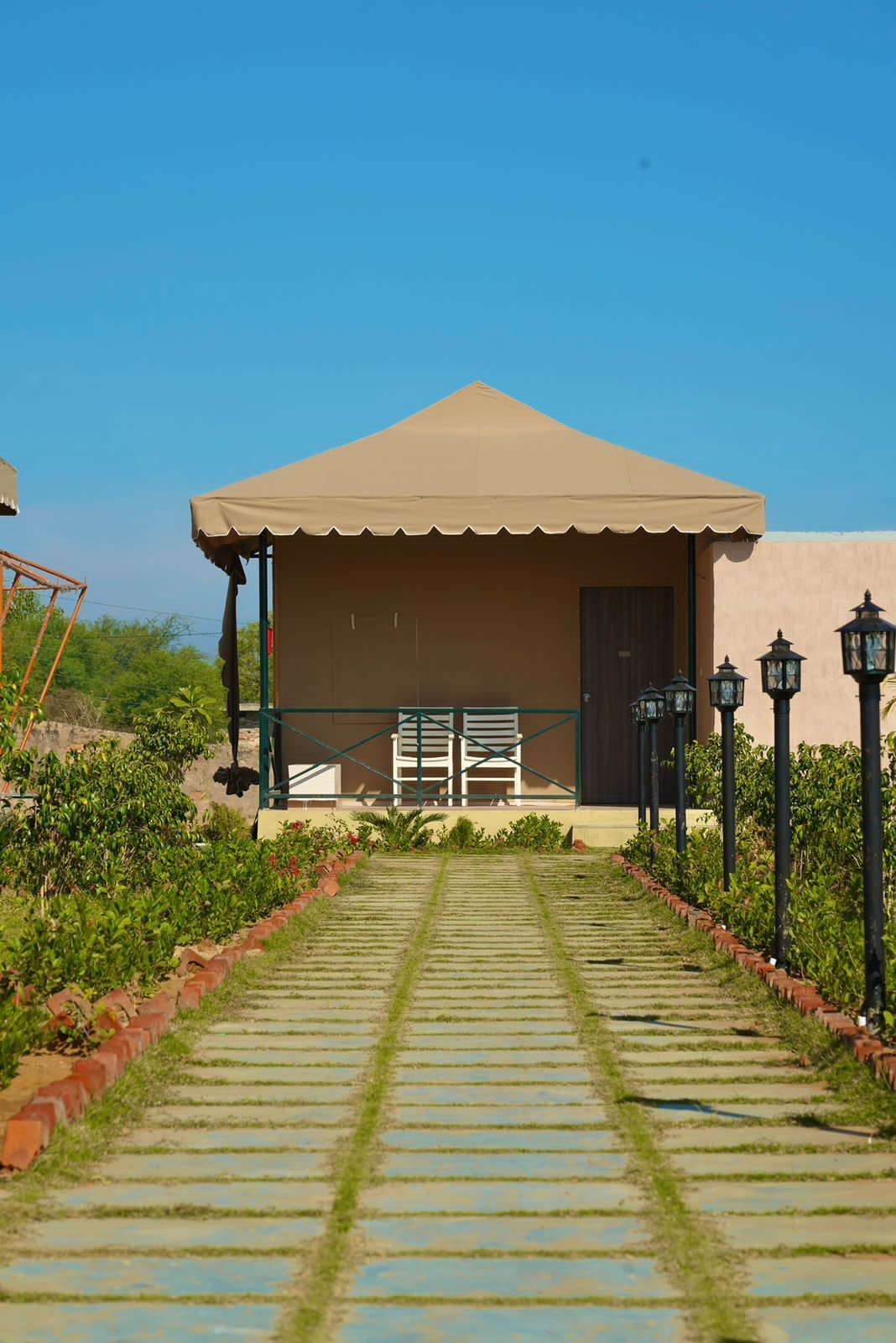 A building with a covered patio area, a pathway leading to it, and a row of chairs.