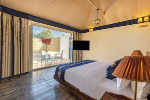 A bedroom with a large bed, a TV mounted on the wall, and a view of the outside.