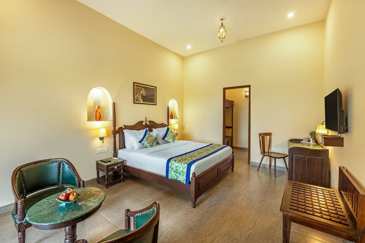 Une chambre d’hôtel avec un lit, deux chaises, une petite table, un téléviseur et un tableau au mur.
