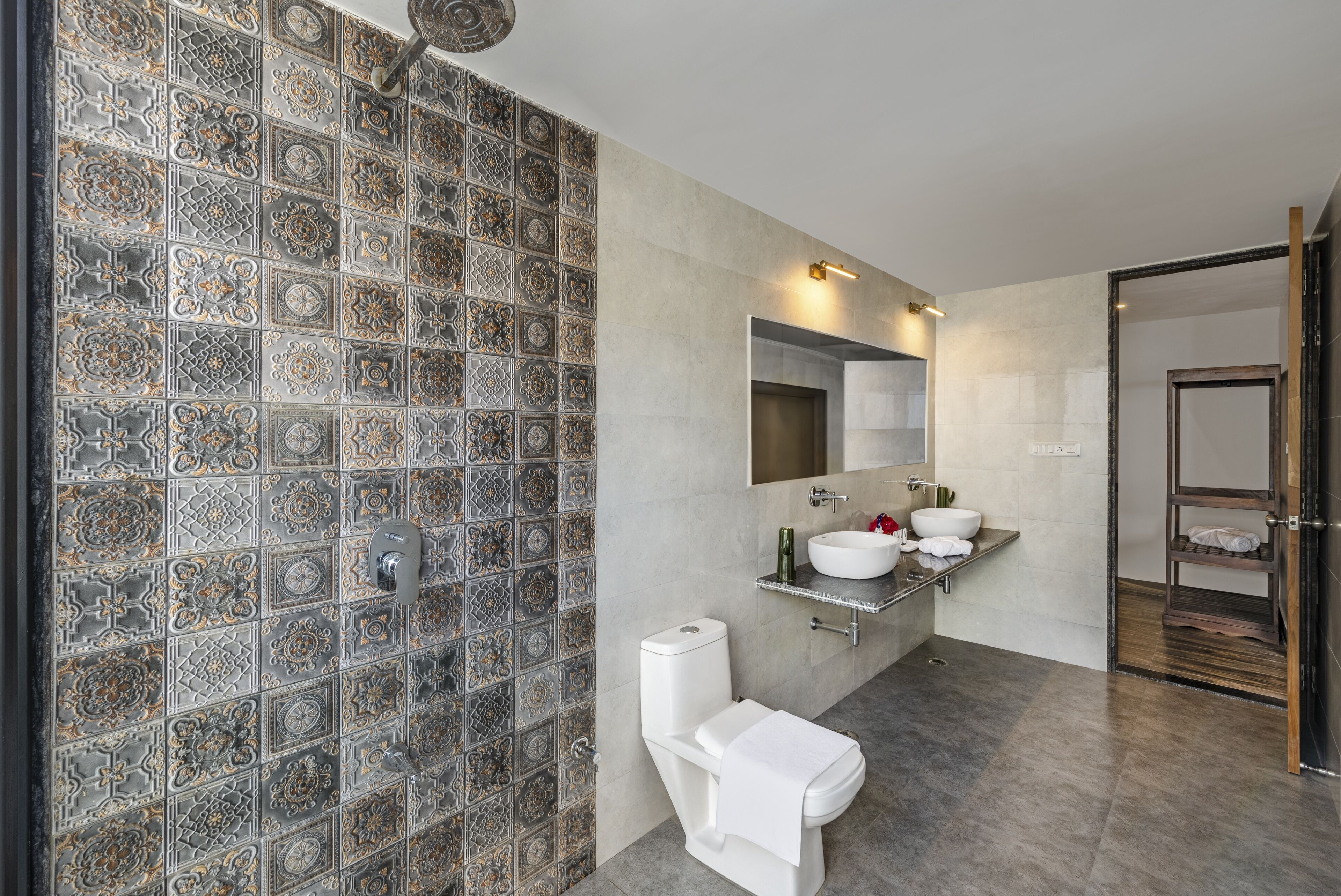 A bathroom with a tiled wall, a toilet, a sink with a mirror, and a shower area.