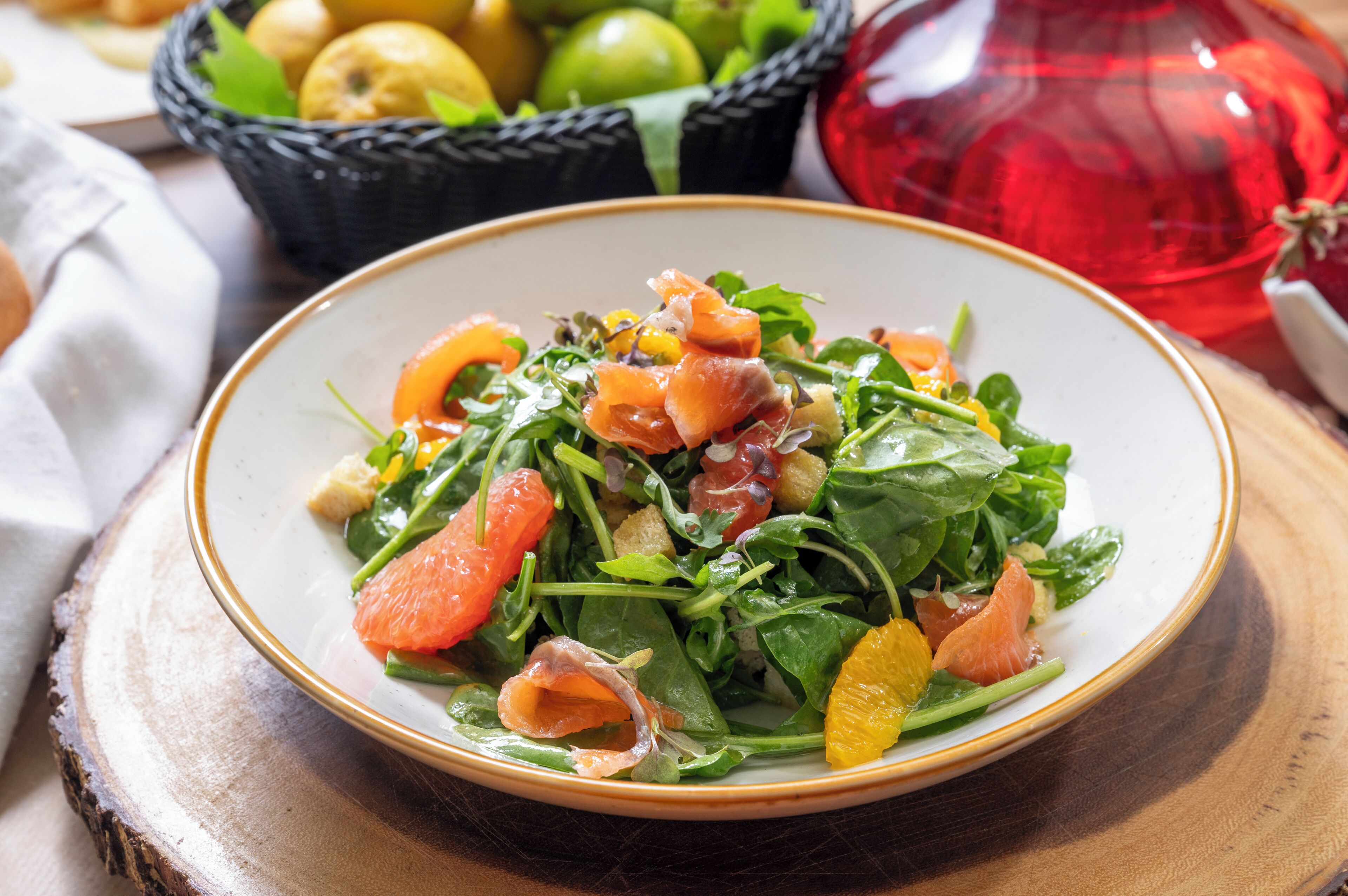 A plate of salad with greens and orange slices on a wooden table.