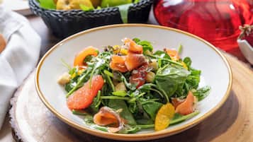 A plate of salad with greens and orange slices on a wooden table.