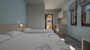 A hotel room with two beds, a small kitchenette, and a view of the outside.
