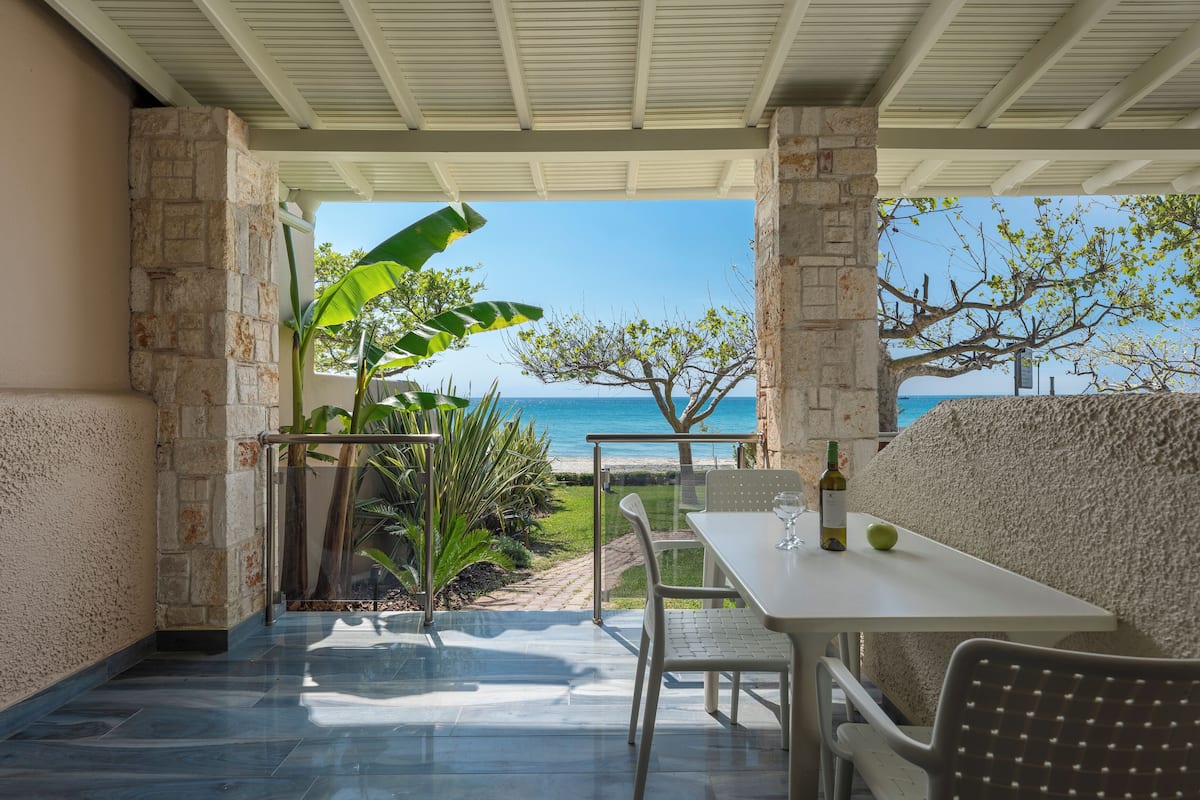 Eine Terrasse mit Tisch und Stühlen, Blick aufs Meer und eine Steinmauer.