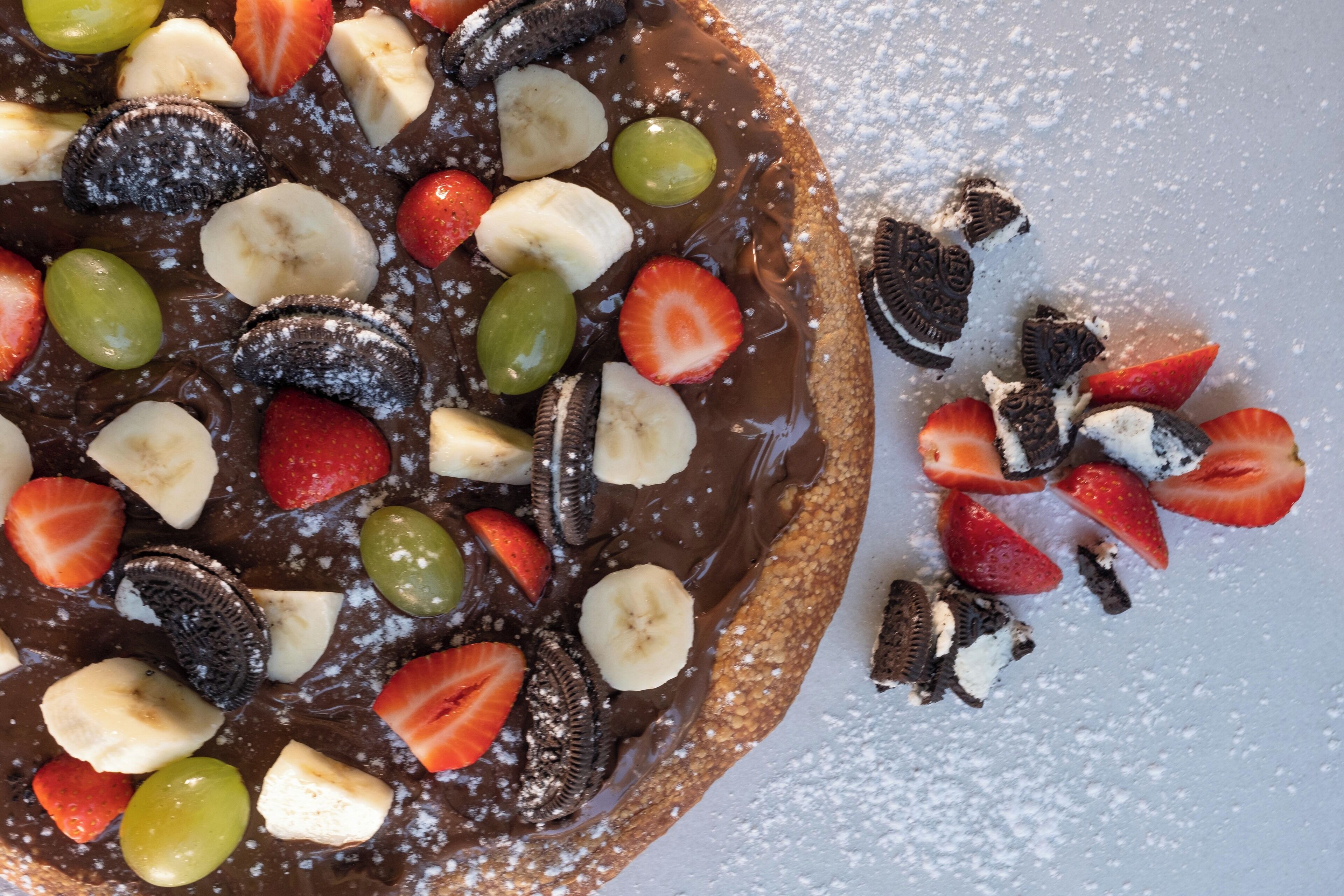 A dessert with chocolate, strawberries, bananas, and green grapes.