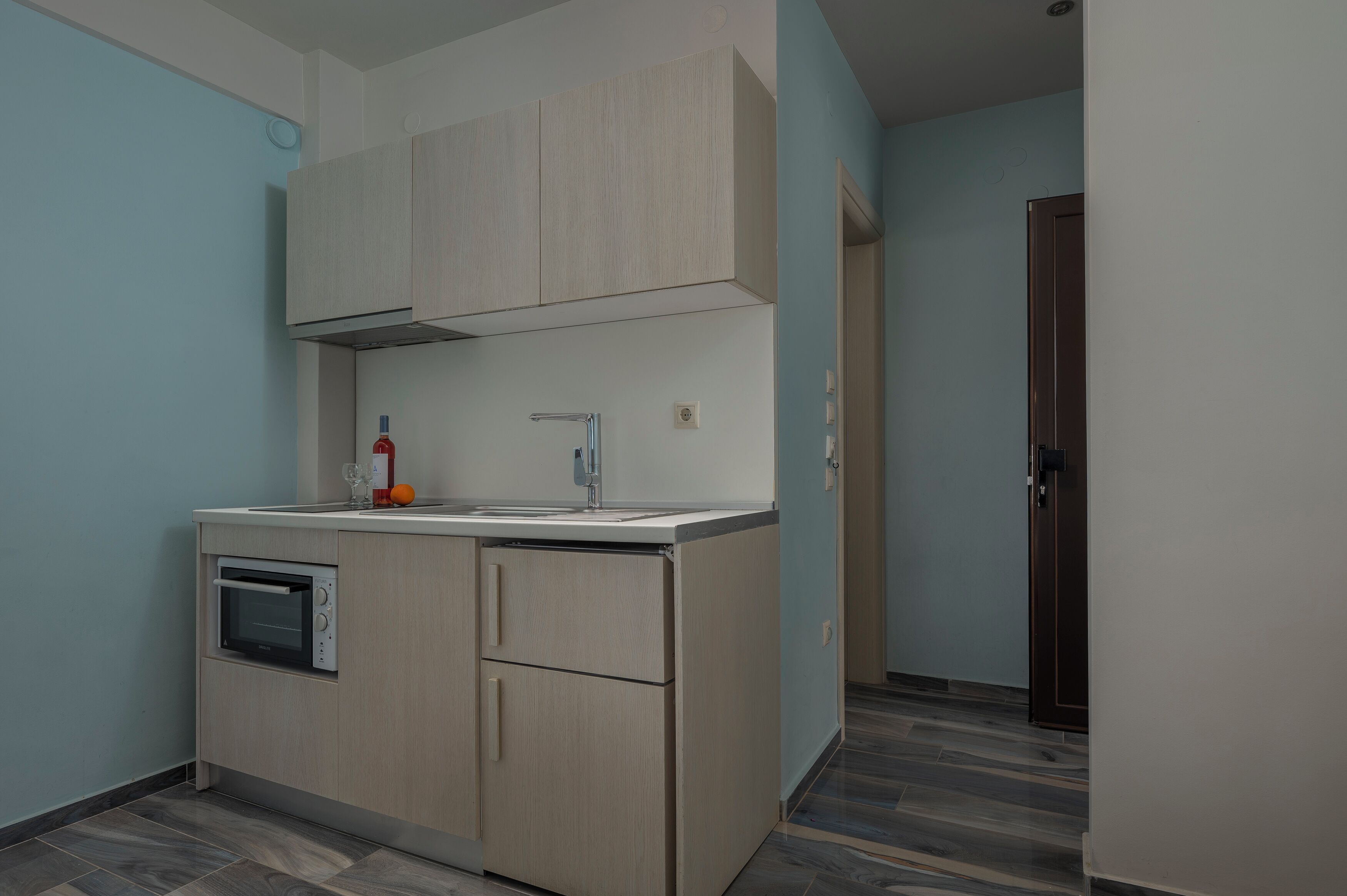 A compact kitchen with a built-in oven, a sink, and a cabinet above the counter.