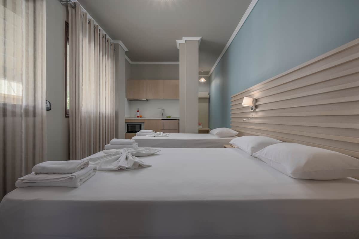Ein Hotelzimmer mit zwei Betten, einer Küchenzeile und einem Badezimmer.