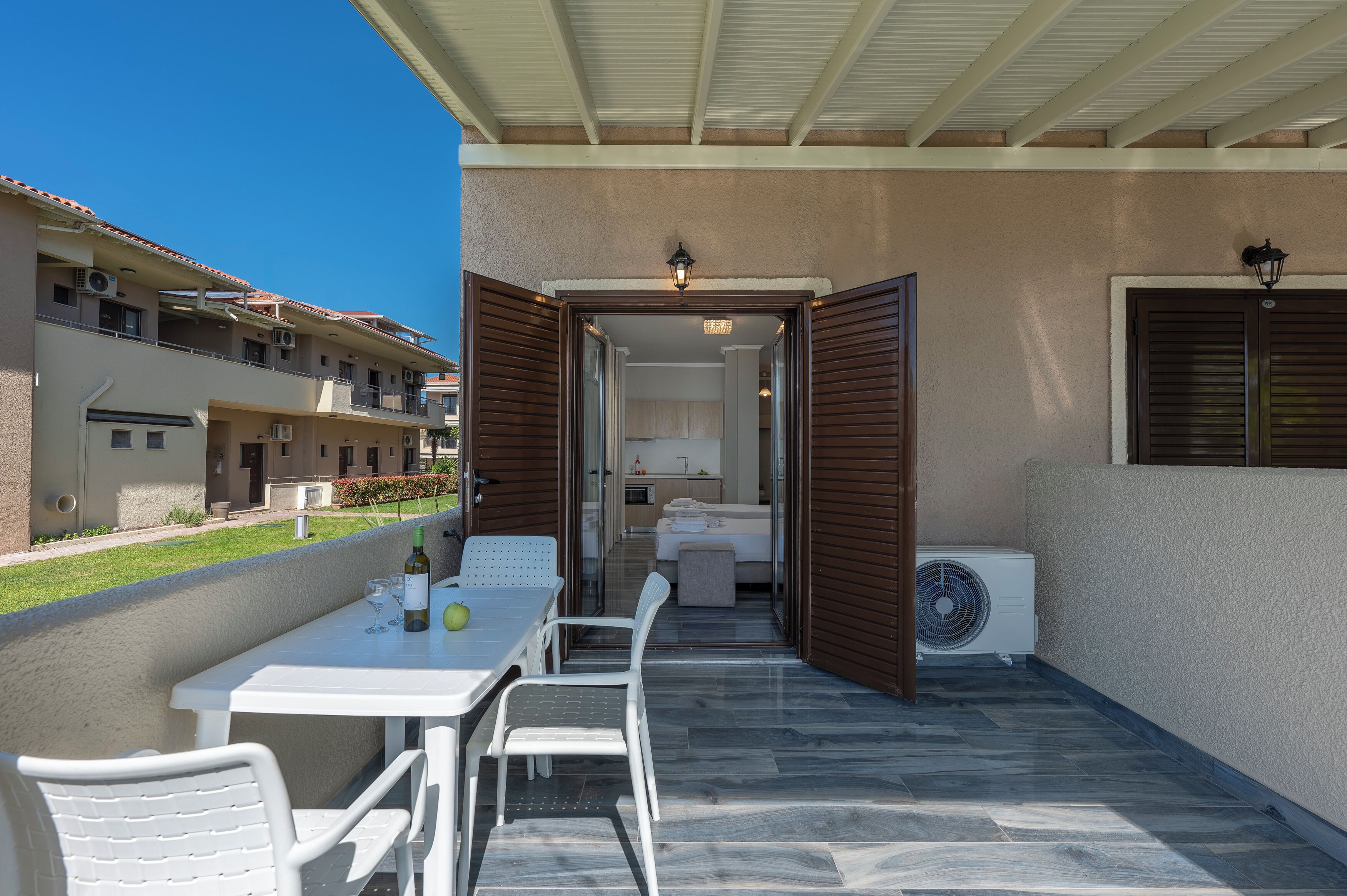 Un balcon avec une table et des chaises, un ventilateur et une vue sur un immeuble doté de balcons.