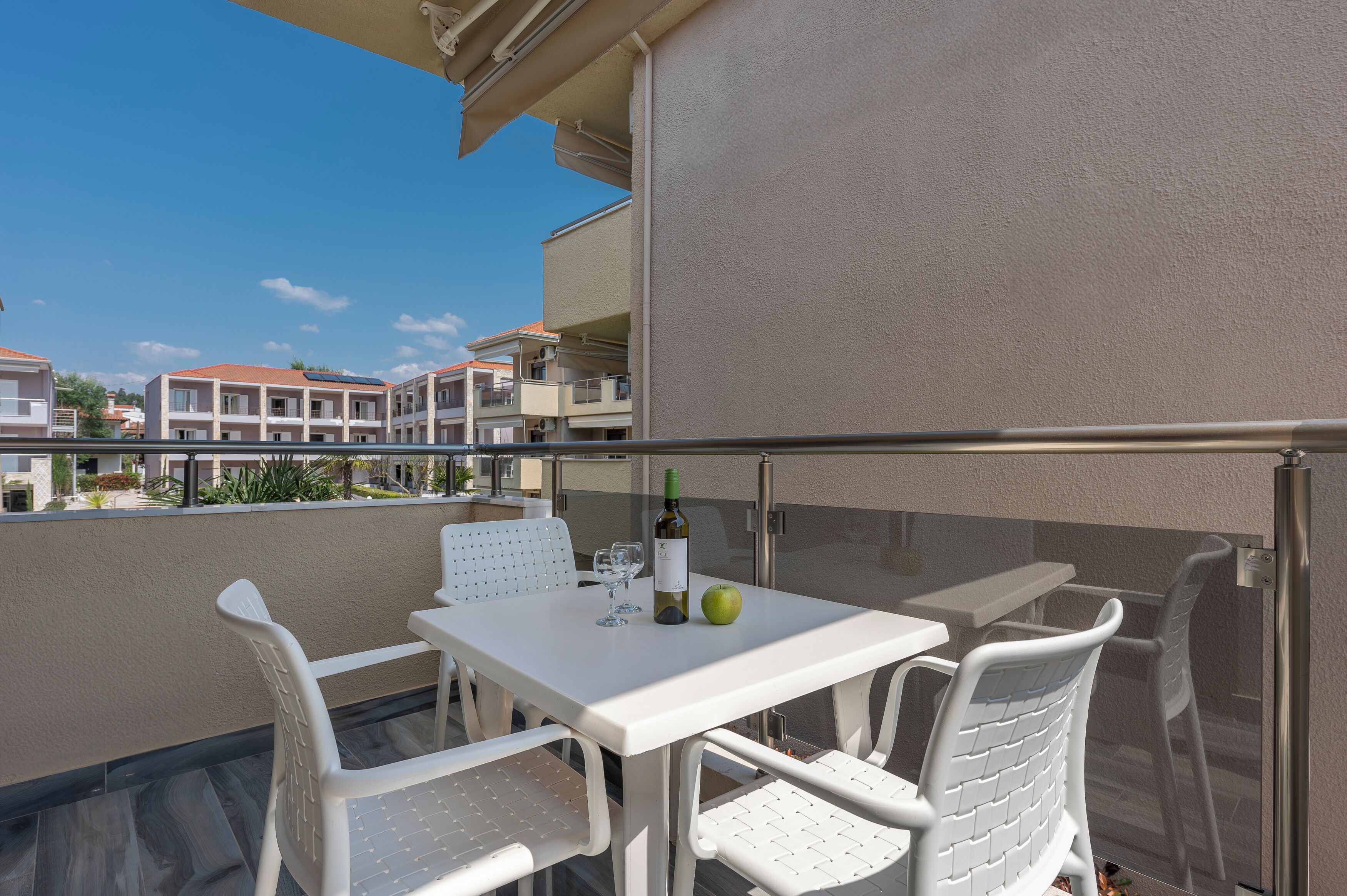A balcony with a table and chairs, a bottle of wine, and an apple.