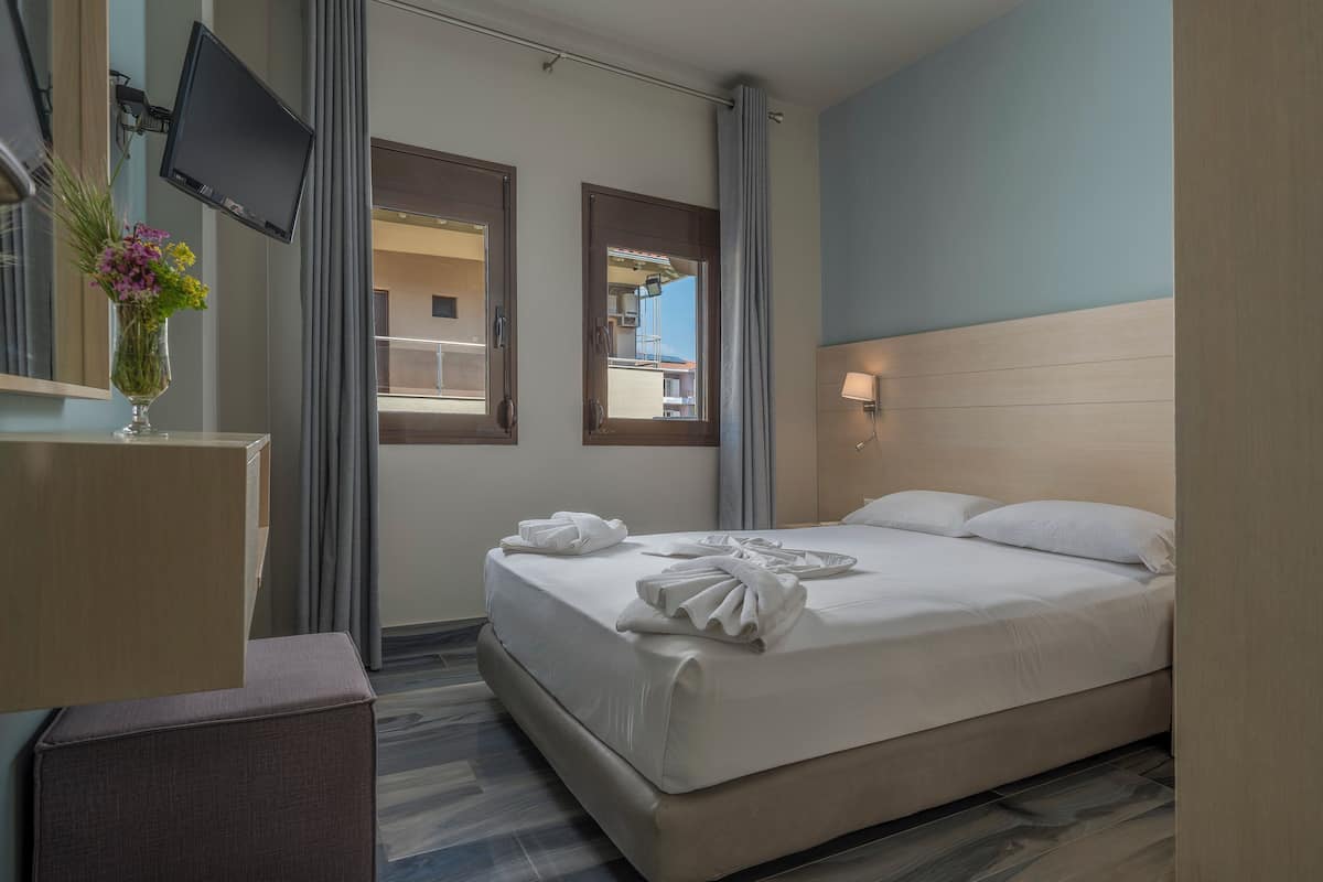 Ein Hotelzimmer mit Bett, Schreibtisch, Fernseher und einem Fenster mit Vorhängen.