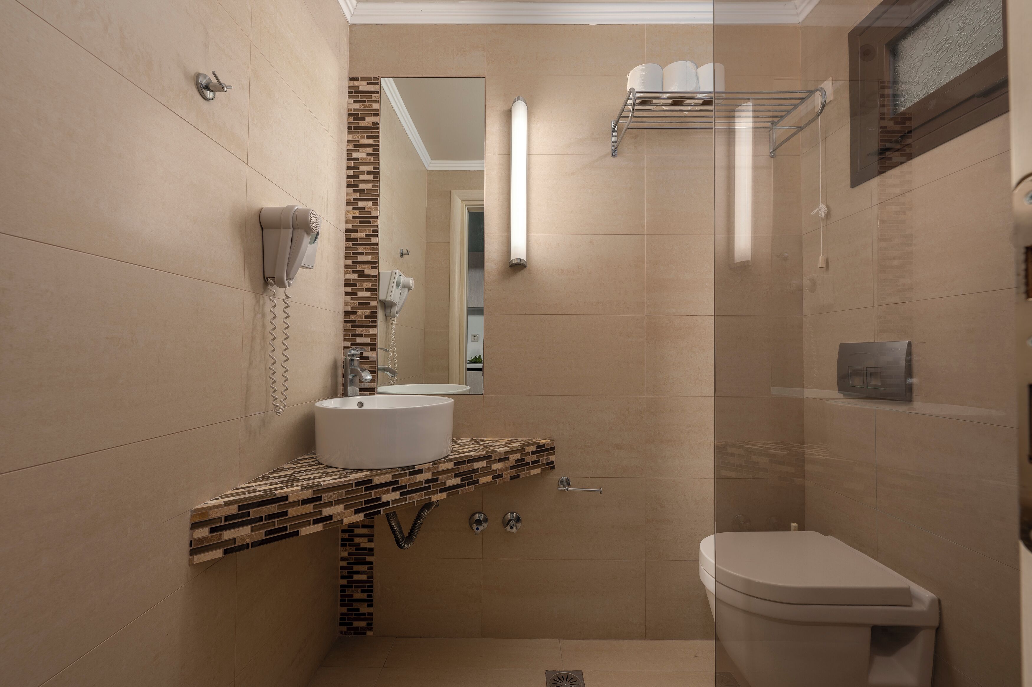 Een moderne badkamer met een grote spiegel, twee wasbakken, een toilet en een douchehoek.