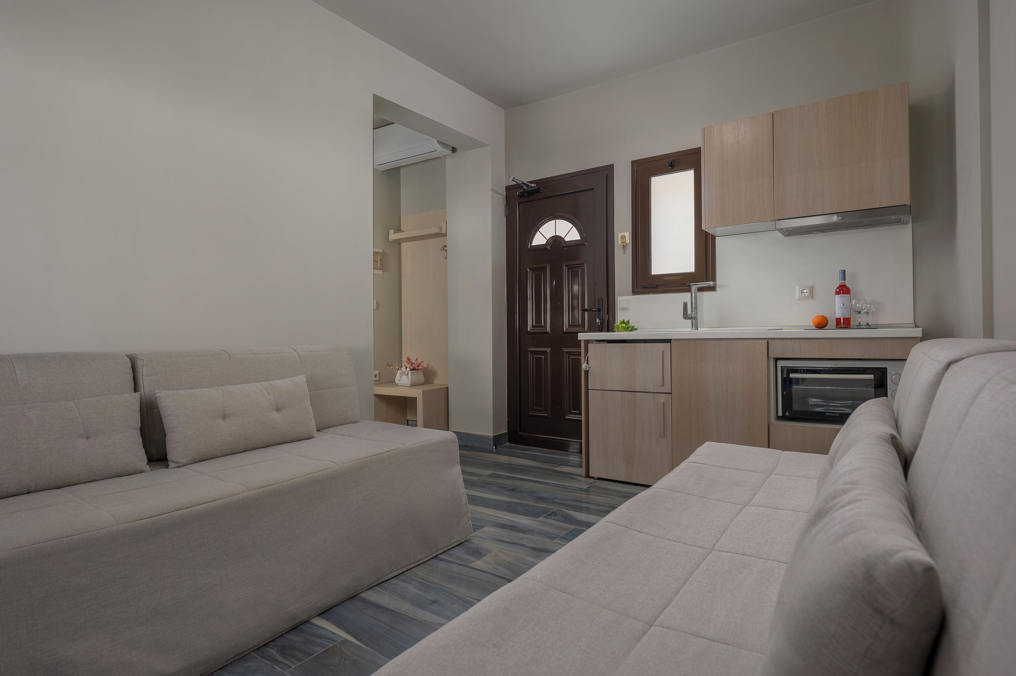 A modern living room with a sofa and a kitchen area including a microwave and cabinets.