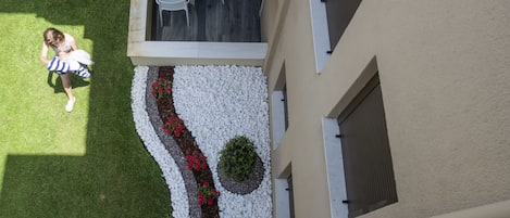 An aerial view of a building with a landscaped garden area featuring white pebbles, red flowers, and a small green bush.
