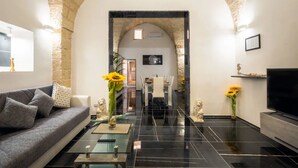 Una sala de estar moderna con un arco de piedra, un sofá, una mesa de centro, un comedor y un televisor.