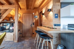 Un interno in legno con angolo cottura, sgabelli da bar e una porta.