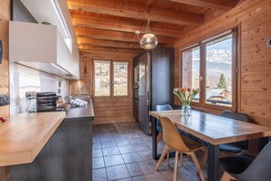 Una cucina moderna con pareti in legno, un'isola centrale e un'area pranzo con vista sulle montagne.