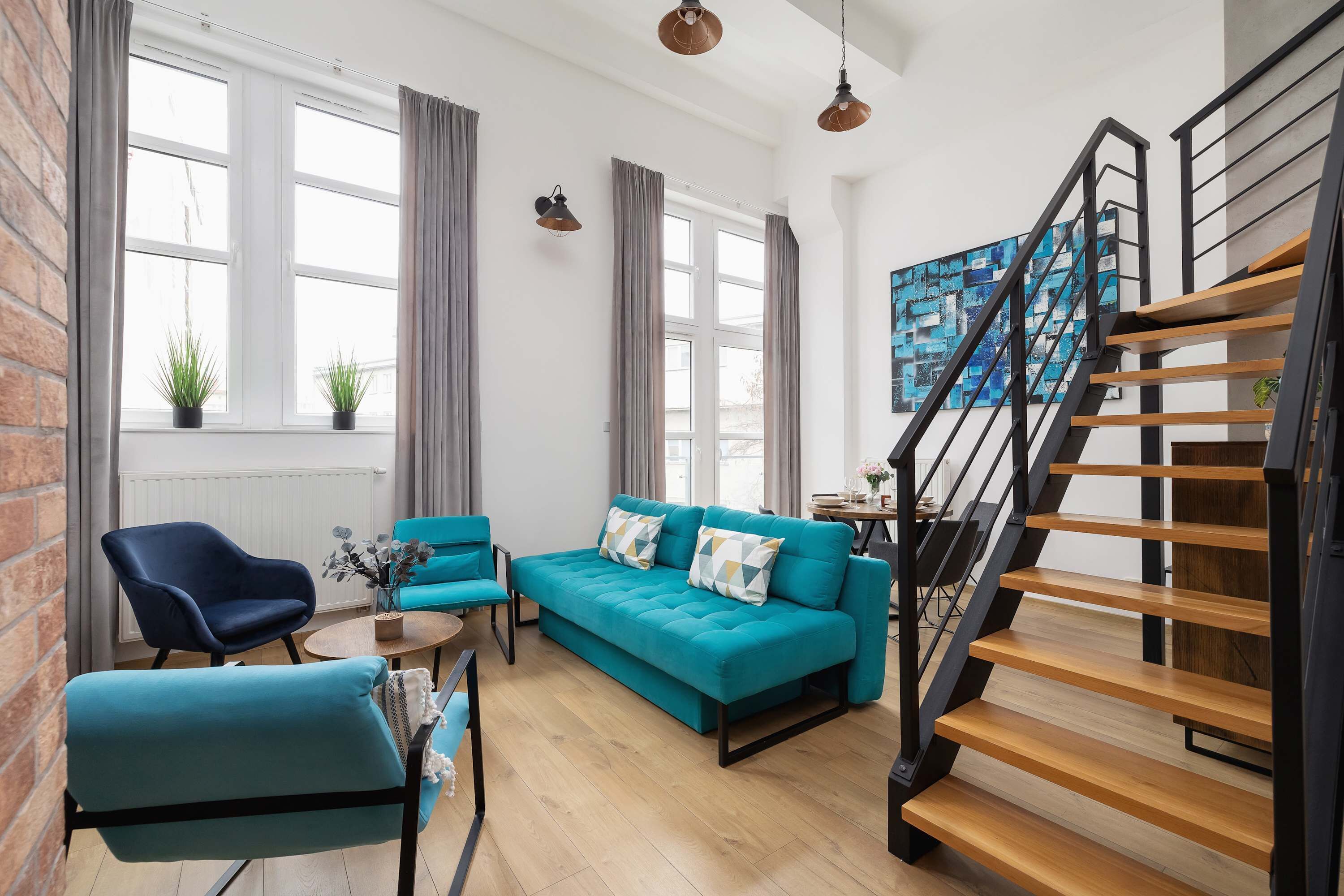 A modern living room with a sofa, chairs, a coffee table, and a staircase.
