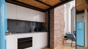 A modern kitchen with white cabinets, a black oven, and a blue refrigerator. - Stylish Studio with Mezzanine | Air Conditioning | Close to the Center (Kraków)